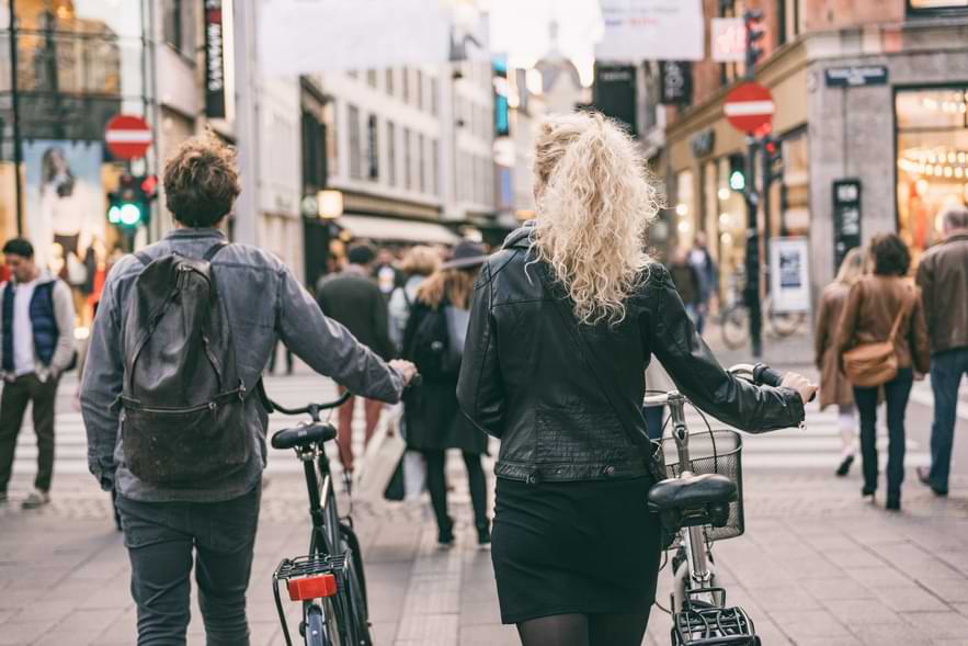 Man och kvinna leder cyklar på gågata