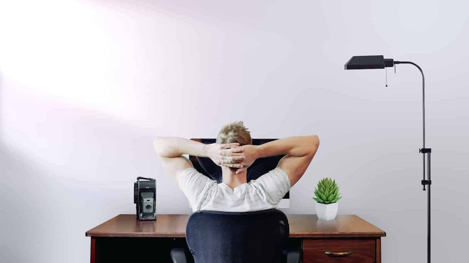 Man håller huvudet i händerna medan han sitter vid skrivbordet, överväger att slå ihop lån på sin dator