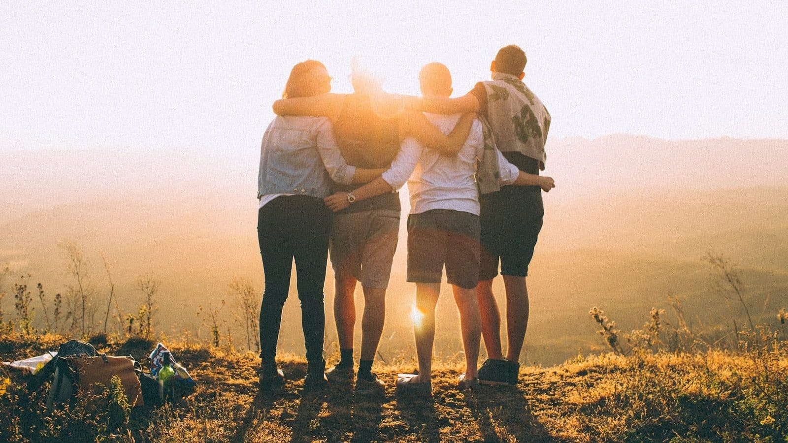 fyra personers händer om varandras axlar medan de ser på solnedgången, symboliserar gemenskap i att uppnå bättre lånevillkor